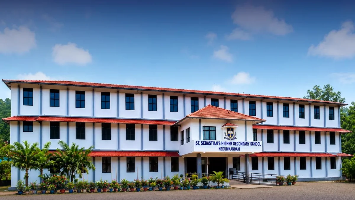 The front of the three-storey main school building, with its red tiled roof and entrance, under a blue sky